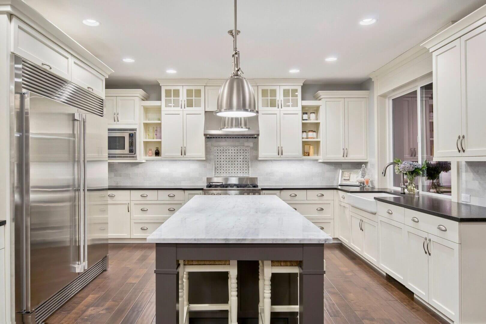 Bright modern kitchen with marble island and white cabinetry.